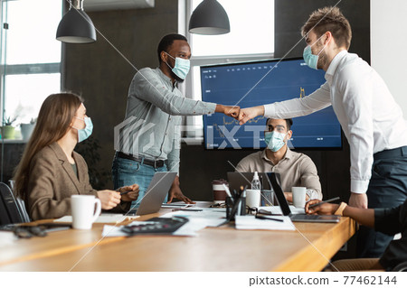 Portrait of diverse business people in masks giving fist bump Portrait of diverse business people in masks giving fist bump 77462144