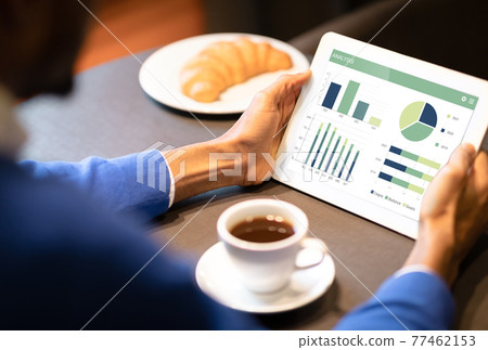 Unrecognizable black businessman analysing market on digital tablet Unrecognizable black businessman analysing market on digital tablet 77462153