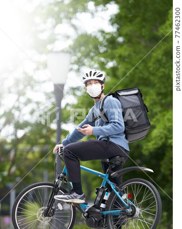 一個戴口罩騎自行車的送貨員 77462300