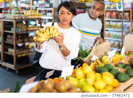 Woman choosing bananas in fruit and vegetable section of supermarket 77462471