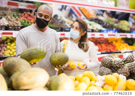 Latin couple choosing fruits in supermarket together during COVID-19 77462819