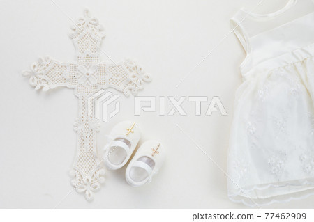 Christening background with baptism dress, shoes, and cross on pastel background 77462909