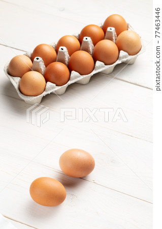 Fresh organic chicken eggs in carton pack or egg container  on white wood background. 77463446