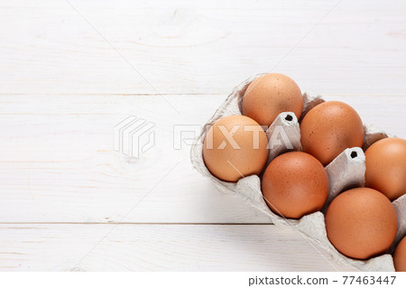 Fresh organic chicken eggs in carton pack or egg container  on white wood background. 77463447