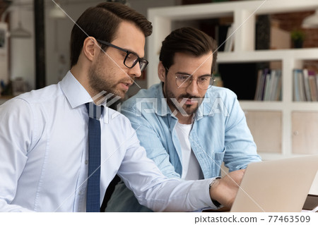 Close up confident mentor pointing finger at screen, training intern 77463509