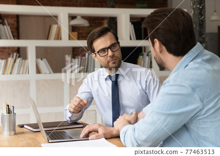 Two colleagues coworkers working on project together, discussing strategy 77463513