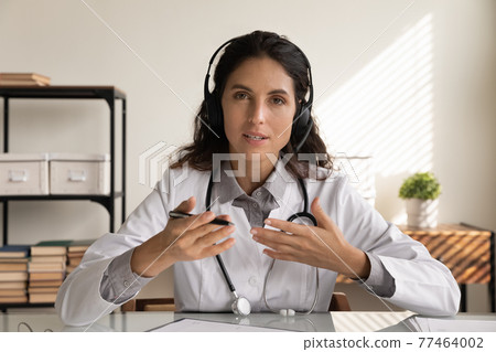 Doctor in headset look at camera share experience with colleagues Doctor in headset look at camera share experience with colleagues 77464002