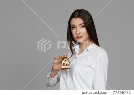 beautiful woman holding little house on gray background. 77466772
