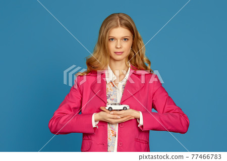 beautiful blonde woman in pink jacket holding a little car beautiful blonde woman in pink jacket holding a little car 77466783