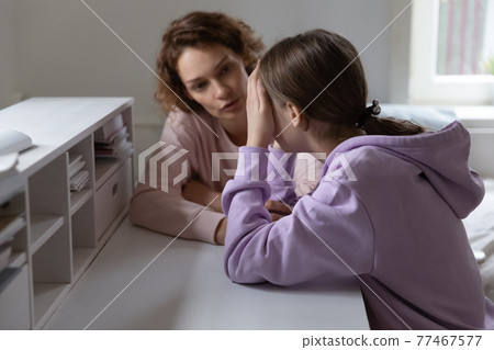Caring mother talking to stressed adolescent daughter. 77467577