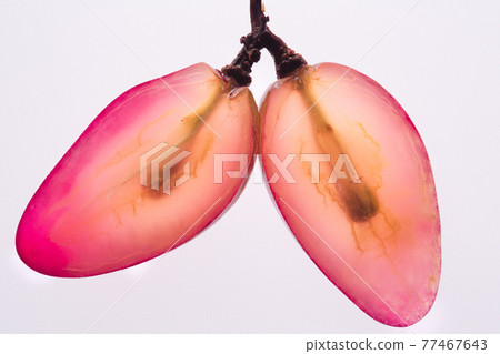 Two Translucent slices of ripe red grapes macro. Isolated on white background. Top view. Two Translucent slices of ripe red grapes macro. Isolated on white background. Top view. 77467643