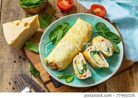 Japanese cuisine. National Japanese dish Omelet tamago yaki for breakfast. Rolled egg with spinach, tomato and cheese on a wooden table. 77468326