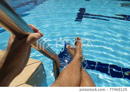 The feet of a young man in a swimming pool in summer, Spain. The feet of a young man in a swimming pool in summer, Spain. 77469129
