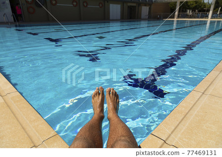 The feet of a young man in a swimming pool in summer, Spain. The feet of a young man in a swimming pool in summer, Spain. 77469131