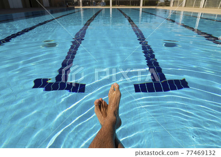 The feet of a young man in a swimming pool in summer, Spain. The feet of a young man in a swimming pool in summer, Spain. 77469132