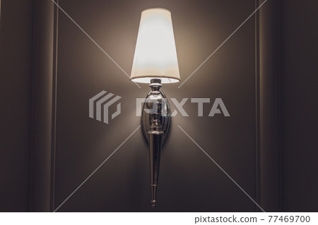 Modern wall lamp on a light wall. Free space and decor in the interior. Modern wall lamp on a light wall. Free space and decor in the interior. 77469700