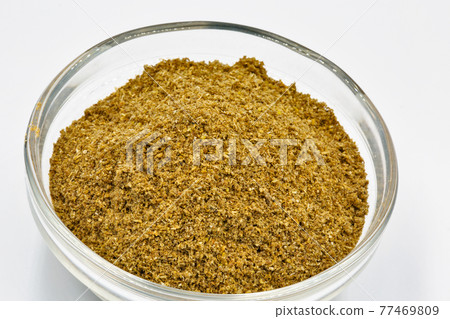 Ground cumin or coriander in glass bowl closeup against white 77469809