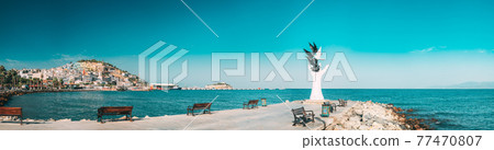 Kusadasi, Aydin Province, Turkey. Waterfront And Kusadasi Cityscape. Hand Of Peace Monument On Waterfront In Sunny Summer Day. View Of Hand Sculpture At Aegean Coast. 77470807