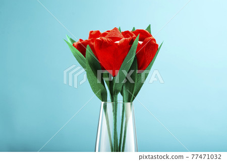 Red tulips made of paper and marshmallows inside the bud on a blue background with place for text 77471032