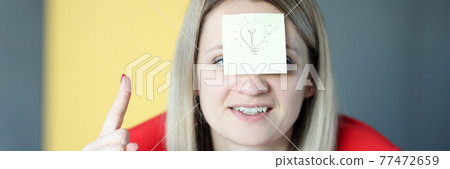 Business woman has sticker with painted light bulb on her face 77472659
