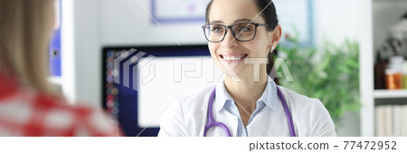 Smiling portrait of doctor in glasses conducts an appointment with patient 77472952