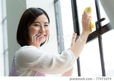Cute woman cleaning the window Cute woman cleaning the window 77473074