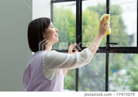 Cute woman cleaning the window Cute woman cleaning the window 77473079