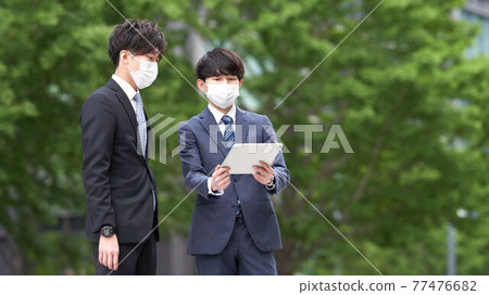 A businessman in a mask having a meeting outdoors A businessman in a mask having a meeting outdoors 77476682