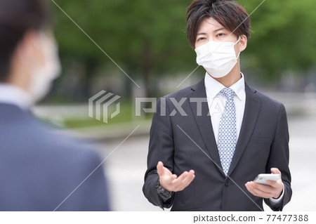 一個戴著面具的商人在戶外打手勢時說話 一個戴著面具的商人在戶外打手勢時說話 77477388