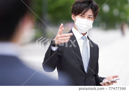 一個戴著面具的商人在戶外打手勢時說話 77477390