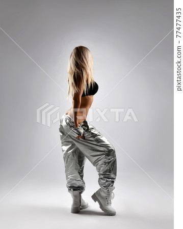 Slim blonde woman in silver loose fit pants, black 77477435