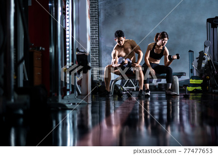 Personal fitness trainer helping woman Practice dumbbells 77477653