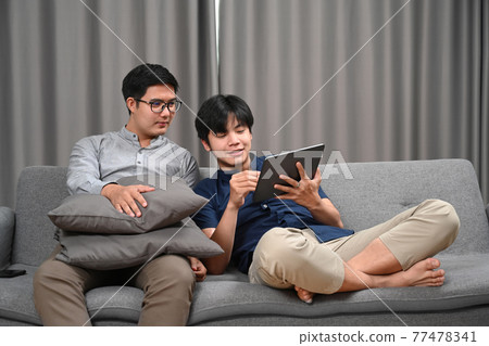 Happy gay couple using digital tablet while spending time together at home. Homosexual, LGBT concept. Happy gay couple using digital tablet while spending time together at home. Homosexual, LGBT concept. 77478341