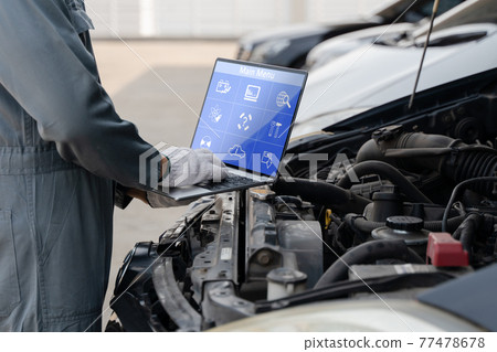 Mechanic using a laptop computer to check collect information during work a car engine. service maintenance of industrial to engine repair. Mechanic using a laptop computer to check collect information during work a car engine. service maintenance of industrial to engine repair. 77478678