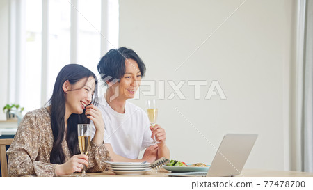 Couple watching a computer while eating Online drinking party watching videos Couple watching a computer while eating Online drinking party watching videos 77478700