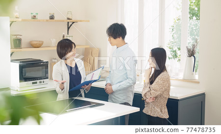 Female person in charge of guiding a couple to a room Model house Housing exhibition hall Finding a room 77478735