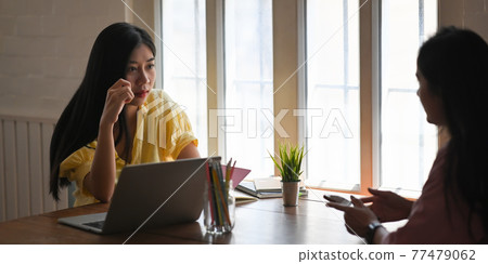 Photo of beautiful women working with computer laptop that putting on wooden working desk while sitting in front her colleague over comfortable living room windows as background. Photo of beautiful women working with computer laptop that putting on wooden working desk while sitting in front her colleague over comfortable living room windows as background. 77479062