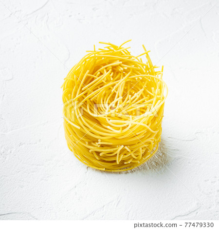 Dried taglierini , on white stone surface, square format Dried taglierini , on white stone surface, square format 77479330