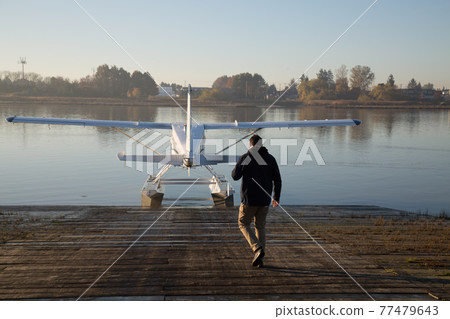 Male pilot walking toward seaplane water 77479643