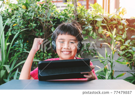 Asian cute boy playing games on the tablet. 77479887