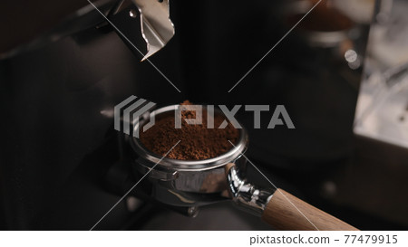 Closeup of grinding fresh coffee into pottomless portafilter Closeup of grinding fresh coffee into pottomless portafilter 77479915