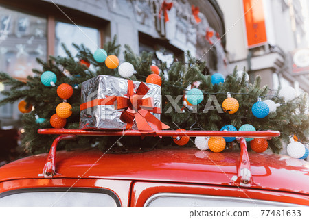 Red retro car with a Christmas tree fir tied to the roof. Red retro car with a Christmas tree fir tied to the roof. 77481633