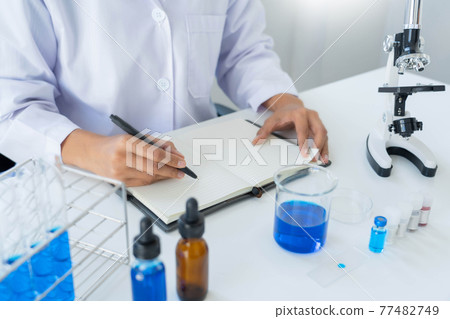 Scientist wear lab coat and protective wear are working with research or doing investigations with test tubes in experiment, Laboratory and development concept 77482749