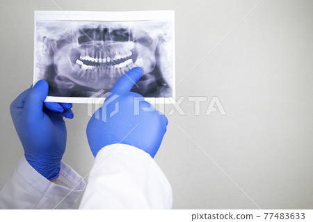 A dentist doctor examines a radiography of the teeth of a patient who has problems and teeth are inserted. The concept of research and diagnosis A dentist doctor examines a radiography of the teeth of a patient who has problems and teeth are inserted. The concept of research and diagnosis 77483633
