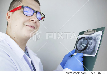 A dentist doctor examines a radiography of the teeth of a patient who has problems and teeth are inserted. The concept of research and diagnosis 77483639