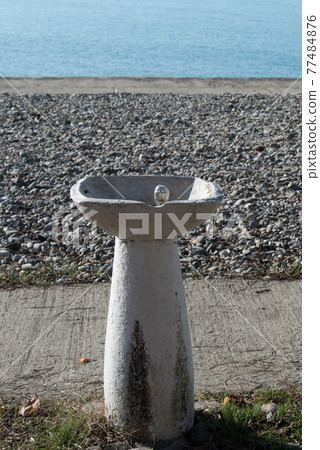 An old fountain with drinking water on the beach is not working. Closed season, pandemic, covid-19 coronavirus. Concept. An old fountain with drinking water on the beach is not working. Closed season, pandemic, covid-19 coronavirus. Concept. 77484876