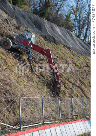 Red spider type excavator in operation on a steep slope. Specialized equipment. Drilling. The strengthening of the slope. Red spider type excavator in operation on a steep slope. Specialized equipment. Drilling. The strengthening of the slope. 77484877