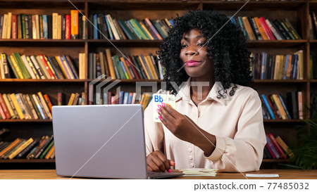 African-American teacher shows cards with letters to screen African-American teacher shows cards with letters to screen 77485032