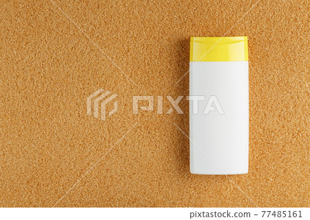 Sunscreen in a white bottle with a yellow cap on the golden sand. Sunscreen in a white bottle with a yellow cap on the golden sand. 77485161