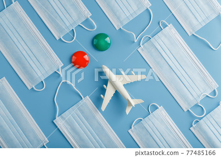 The plane is surrounded by medical masks on a blue background with a red green dot of the destination. 77485166